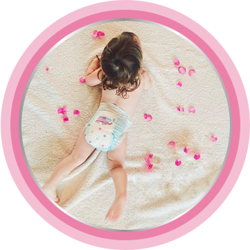 Newborn laying in bed with rose petals as soft as baby skin moisturizing cream.